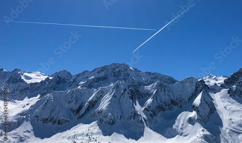 Airplane tracks over the Italian alps. Blue bird day in the mountains.