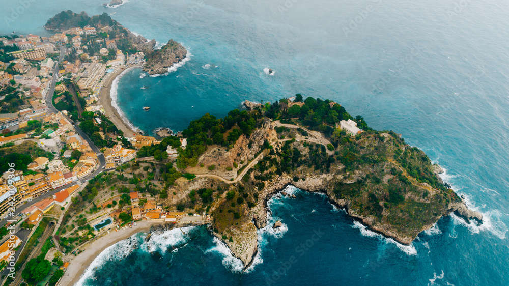 Aerial view of charming coastal Mediterranean small town on Sicily island, Taormina. Beaches of Taormina and south Italy.Travel destination, vacation in Italy concept.Aerial landscape of Bella Isola