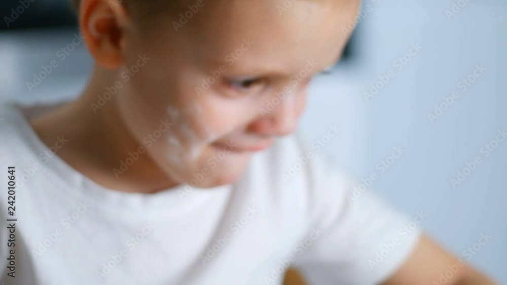 Little kid preparing dough on the table and sneezes. Little baby playing with flour. Baker prepares the dough Little kid preparing dough on the table and sneezes. Little baby playing with flour. Baker prepares the dough