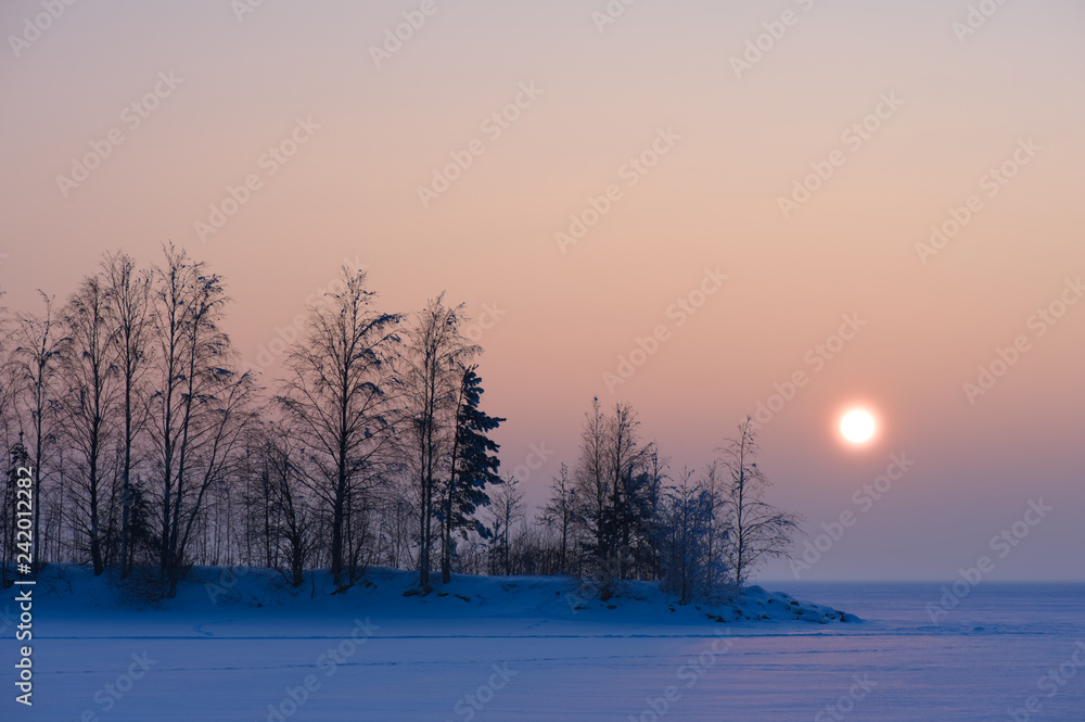 Sunshine over frozen lake on a cold winter day.