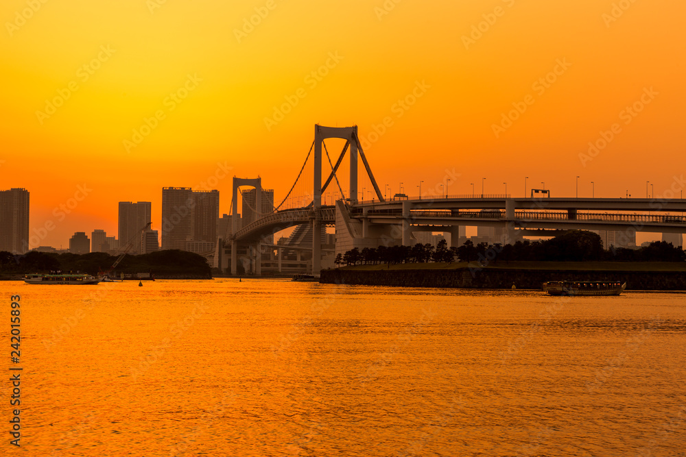 Tokyo skyline and rainbow bridge at sunset in Odaiba waterfront.