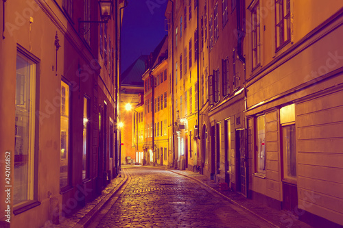 The narrow cobblestone street with medieval houses of Gamla Stan historic old center of Stockholm in the evening twilight sunset. Toned image © Nikolay N. Antonov