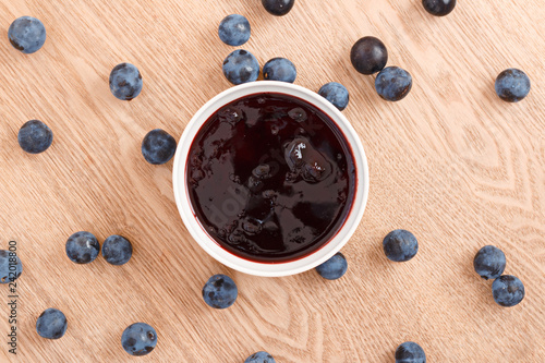 The composition of sweet organic sloe jam in a bowl with a wooden background. Top view