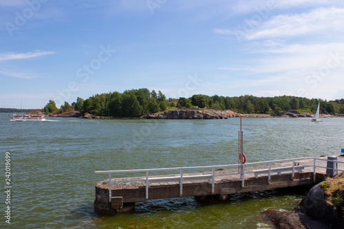 Pier on the shore, ferry and island in the Gulf of Finland in Finland on a summer day.