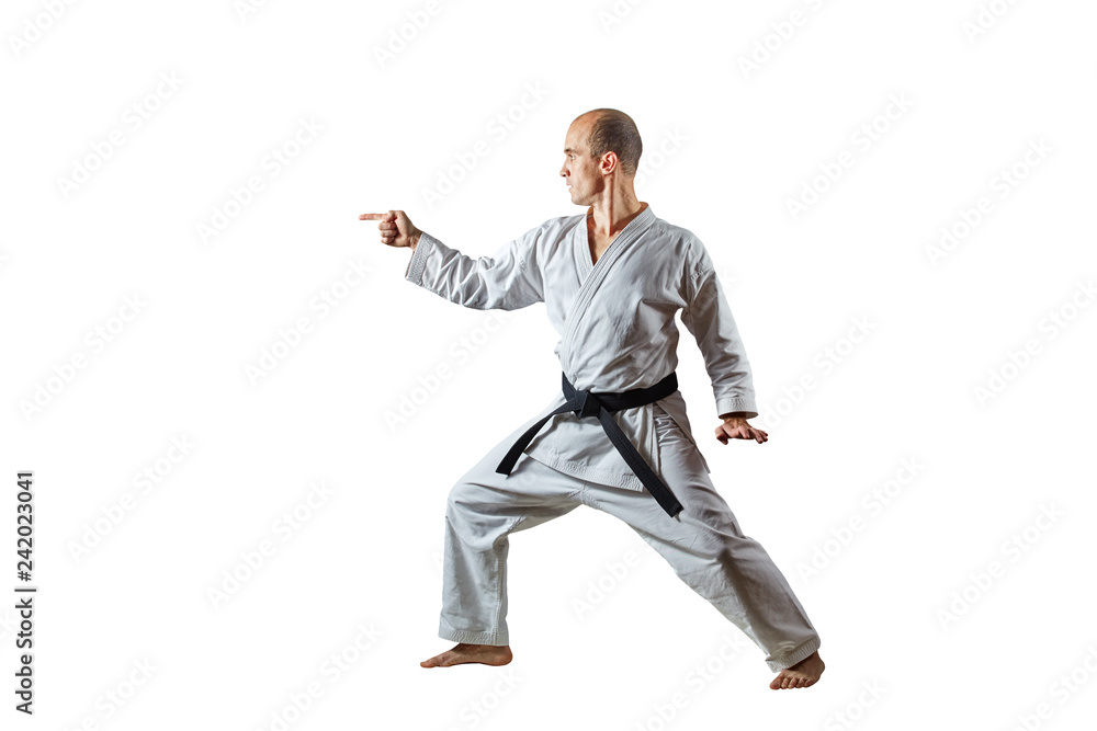 Adult athlete with a black belt trains formal karate exercises on a white isolated background