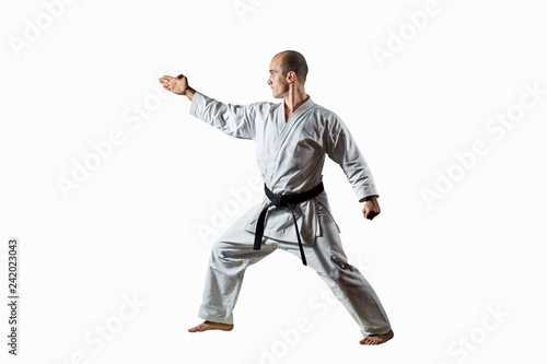 Adult male athlete doing formal karate exercises on a white isolated background