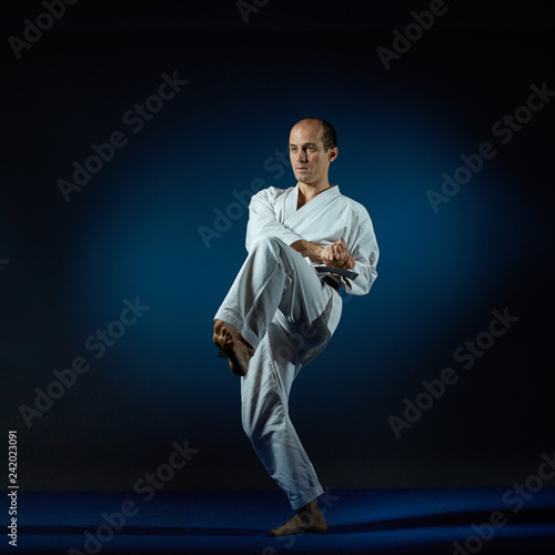 Black belt athlete trains formal karate exercises on blue tatami