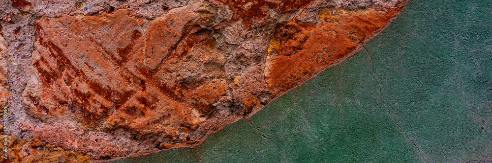 Fototapeta premium brick wall covered with old crumbling cement plaster with traces of paint.
