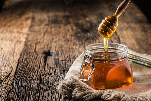 Obraz na płótnie Honey jar with dipper on old woodn table