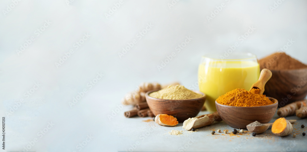Φωτογραφία Healthy vegan turmeric latte or golden milk, turmeric root, ginger powder, black pepper over grey concrete background