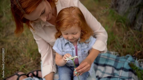 mother and little daughter tell fortune on daisy