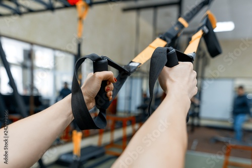 Close-up female hands with fitness straps in gym. Sport, fitness, training, people concept.