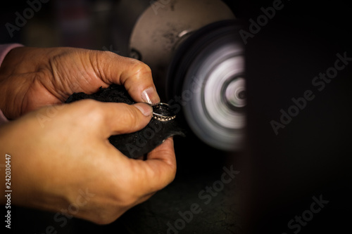 Jeweler polishes gold ring on bench grinder in jewellers workshop