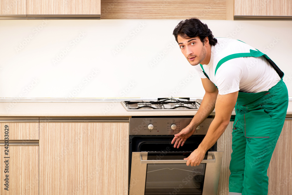Young contractor repairing oven in kitchen Young contractor repairing oven in kitchen