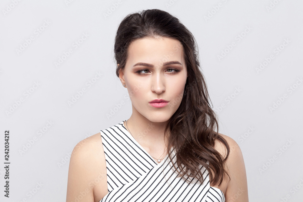 Portrait of crazy funny beautiful young brunette woman with makeup and striped dress standing and looking at camera with crossed eyes. indoor studio shot, isolated on grey background. Portrait of crazy funny beautiful young brunette woman with makeup and striped dress standing and looking at camera with crossed eyes. indoor studio shot, isolated on grey background.