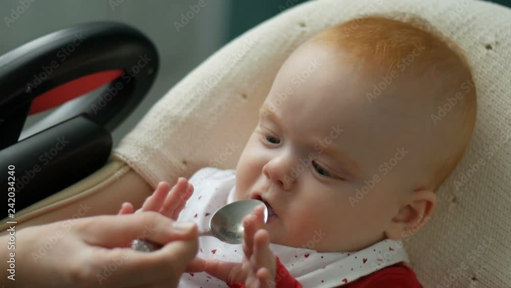 Mother gives baby food from a spoon Mother gives baby food from a spoon