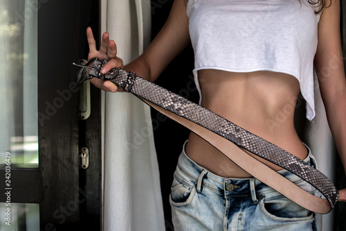 Fashion luxury snakeskin leather belts outdoors. Girl holsing Python belts on expensive villa. top view. social media, advertising, wearing stylish jeans, Trendy casual outfit.Place for text