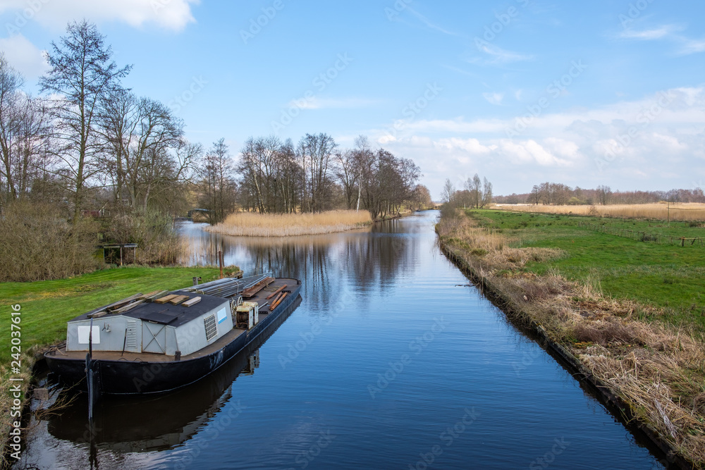 Early spring view on Giethoorn, Netherlands, a traditional Dutch village with canals. A typical low boat along the lawn in a ditch.