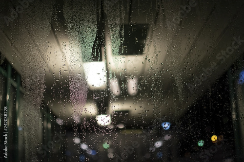 Abstract moody dew view on window with lights in commuter train transit area