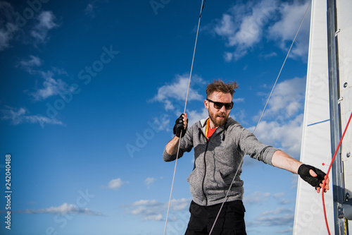 A handsome bearded man in sunglasses on a boat on a river or lake. Beautiful happy guy swimming in a boat on a autumn sunny day feeling free enjoying life