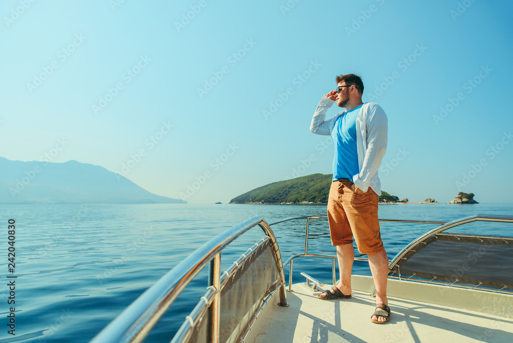 success man standing at nose of boat with sea and mountains on background success man standing at nose of boat with sea and mountains on background
