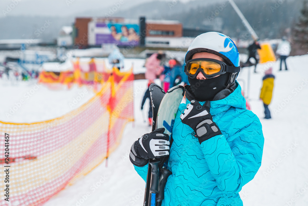 Naklejka premium young adult woman in sport ski wear in helmet and eyeglasses. ski resort on background