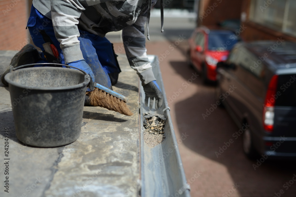 Dachdecker Arbeiter in blauen Handschuhen: Zink Dachrinne mit Handfeger reinigen Dachdecker Arbeiter in blauen Handschuhen: Zink Dachrinne mit Handfeger reinigen