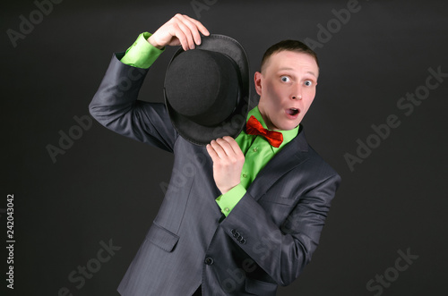 Scared businessman is looks out from a bowler hat in his hands on a black background. Conspiracy concept. photo