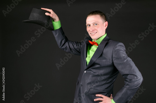 The magician is permorming a magic trick and showing a copy space under his bowler hat on a black background. photo