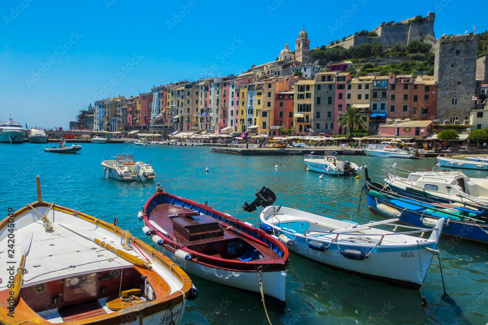 Portovenere, Italy. view of the fishing village of Portovenere from the marina. In the foreground small fishing boats. In the background colorful houses dominated by the walls of the Doria