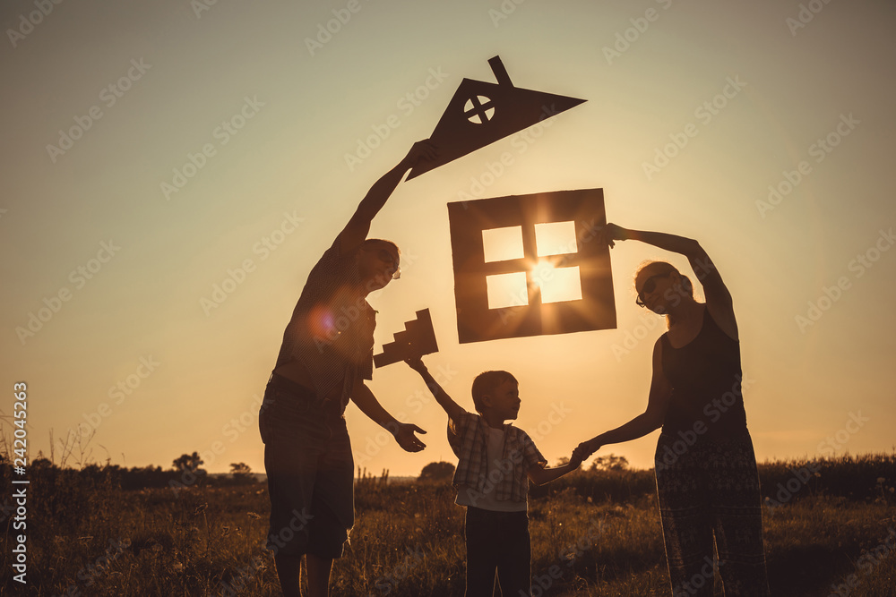 Happy family standing on the field at the sunset time. - obrazy, fototapety, plakaty 
