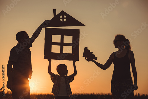 Happy family standing on the field at the sunset time.