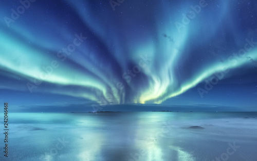 Aurora borealis on the Lofoten islands  Norway. Green northern lights above ocean. Night sky with polar lights. Night winter landscape with aurora and reflection on the water surface. 