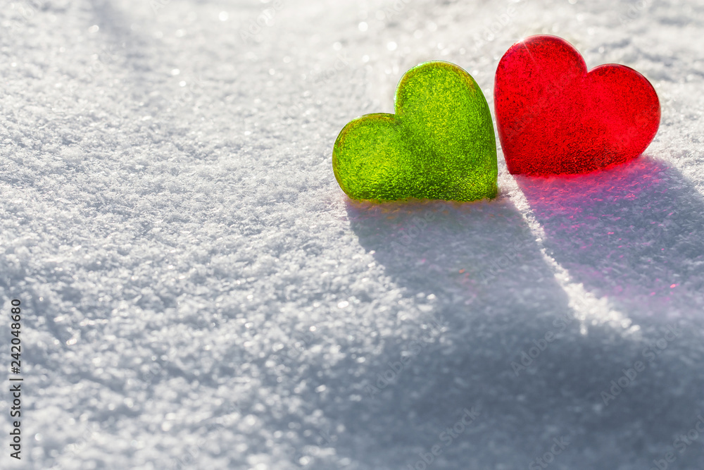 Fototapeta premium Two glass hearts on light background, green and red heart, white snow pattern, love and Saint Valentine day concept