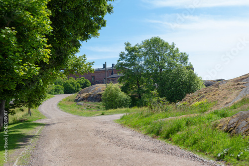 Country road  trees and old buildings are part of the natural Finnish landscape on Suomenlinna Island in Finland on a summer day.
