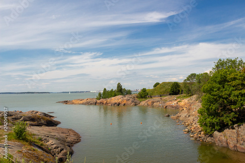 The beautiful rocky shore of the island of Sumenlinna Sveaborg with grass and trees is a favorite holiday destination of Finnish residents in the summer, the Gulf of Finland, a sunny summer day.