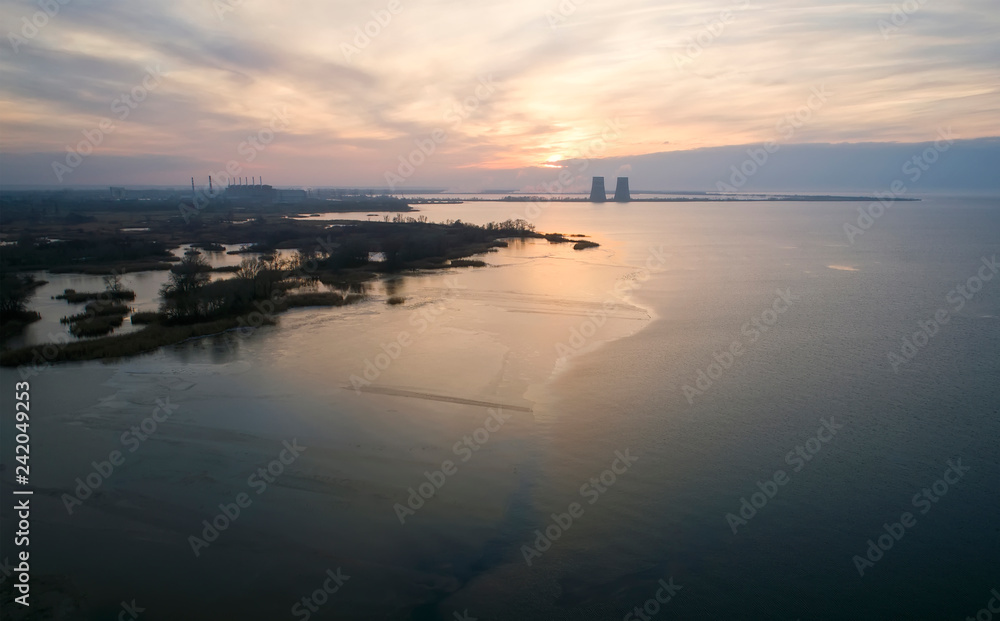 Fototapeta premium Aerial view of a nuclear powerplant in the city of Energodar, Ukraine. Winter landscape, sunset sky.