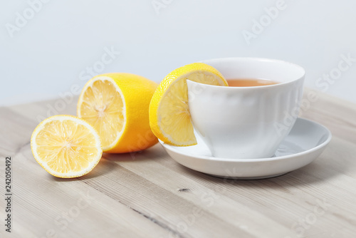 tea with lemon in a white Cup on a saucer on a wooden surface