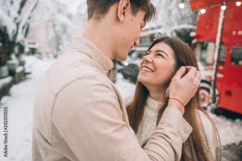 young guy and beautiful girl kiss in a snowy park. Couple in sweaters.