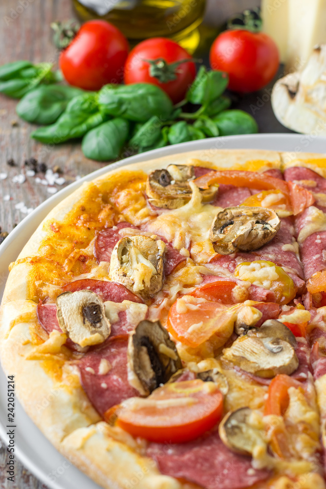 Italian pizza with ingredients on a wooden background, close up Italian pizza with ingredients on a wooden background, close up