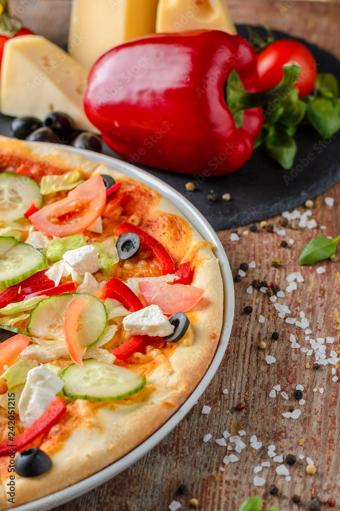 Vegetarian pizza with vegetables and ingredients on a wooden background, close up. Healthy food Vegetarian pizza with vegetables and ingredients on a wooden background, close up. Healthy food