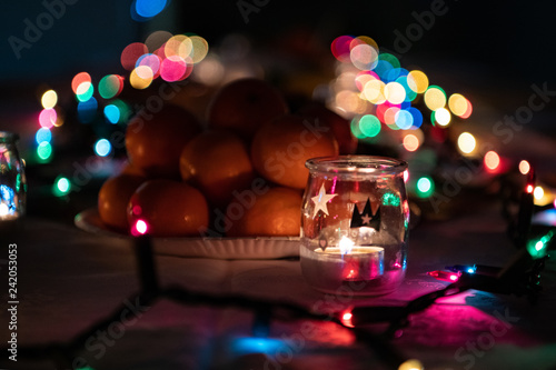 Mandarynki i świeczka na tle świątecznych światełek
