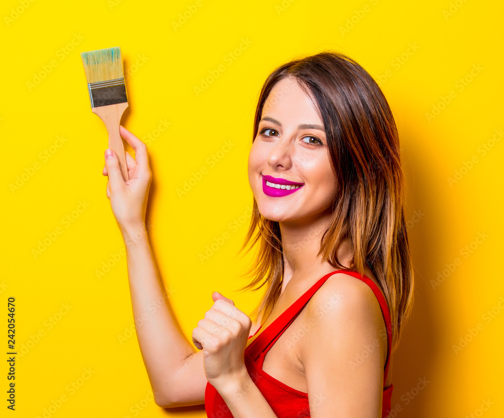 Young girl in red dress with brush on yellow background Young girl in red dress with brush on yellow background