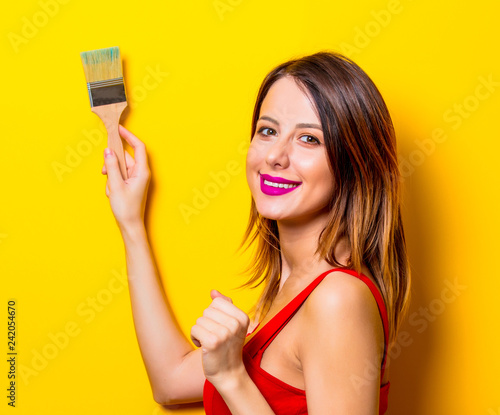 Young girl in red dress with brush on yellow background