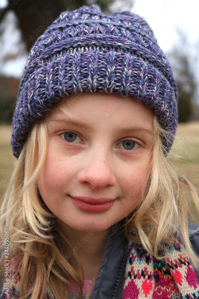 Portrait of a young blond blue eyed girl wearing a purple beanie hat in the cold Portrait of a young blond blue eyed girl wearing a purple beanie hat in the cold