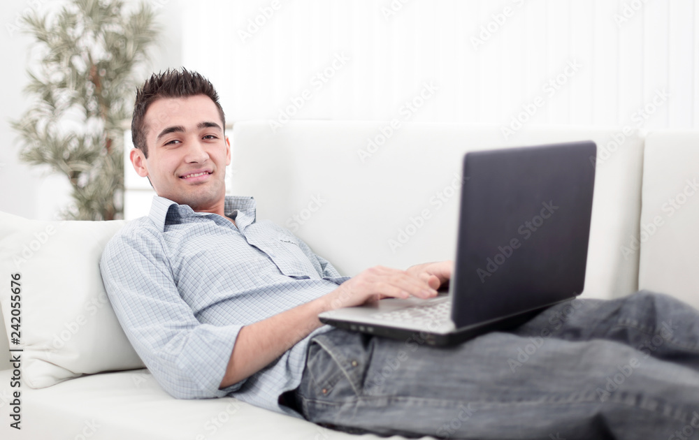 guy with laptop lying on the sofa guy with laptop lying on the sofa