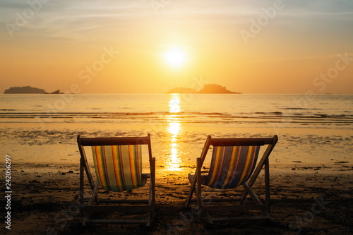 Sun loungers on the sea beach during amazing sunset.