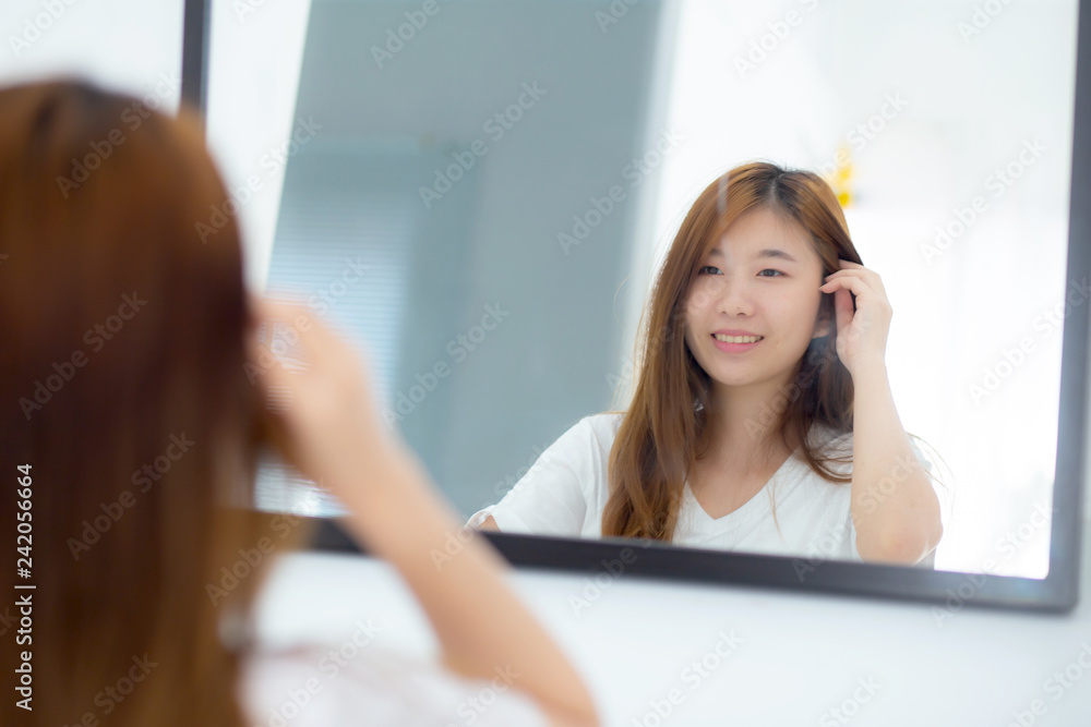 Beautiful of portrait asian young woman examining with face and smile looking on mirror at bedroom, girl beauty of makeup and dressed up with reflection, lifestyle and wellness concept. Beautiful of portrait asian young woman examining with face and smile looking on mirror at bedroom, girl beauty of makeup and dressed up with reflection, lifestyle and wellness concept.