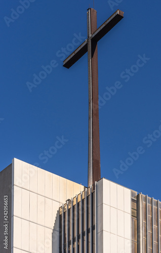 Garden Grove, California, USA - December 13, 2018: Crystal Christ Cathedral. Closeup of cross on top of tower of Hope against blue sky, White stone as base.