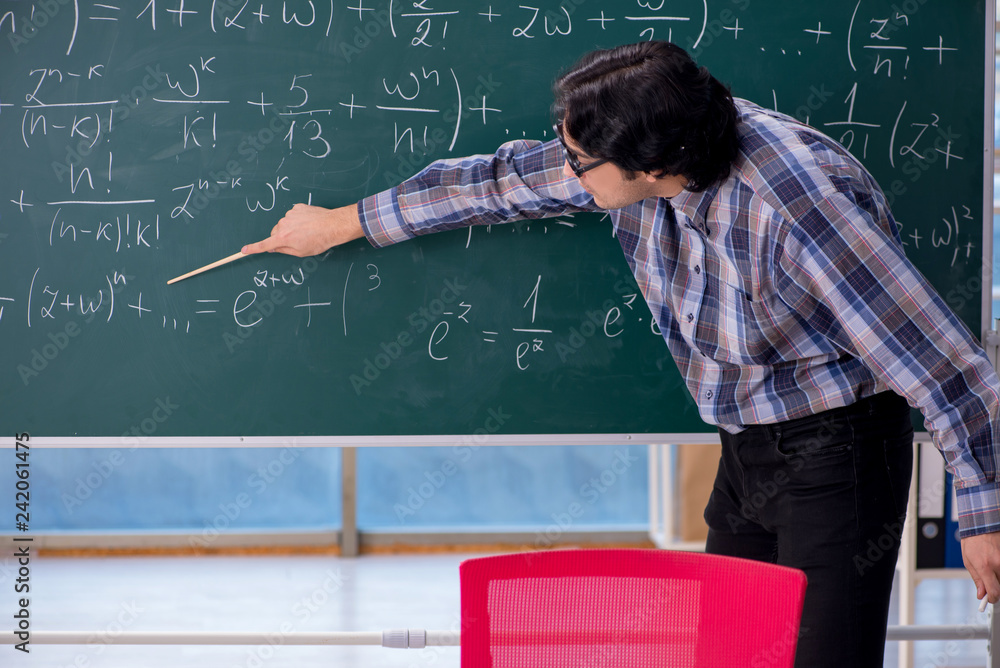 Young funny math teacher in front of chalkboard Young funny math teacher in front of chalkboard
